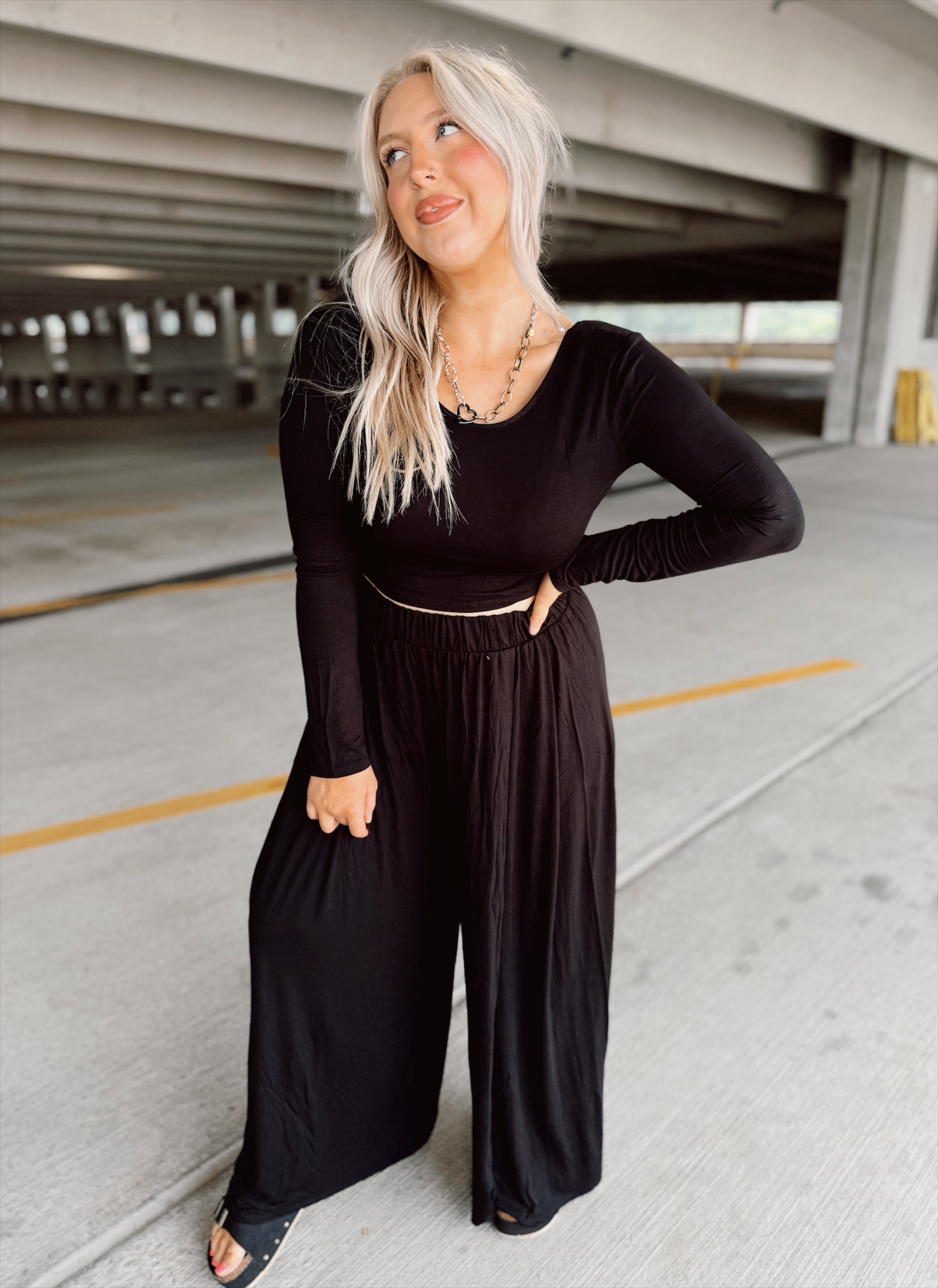 Woman wearing a black outfit in an indoor parking garage.