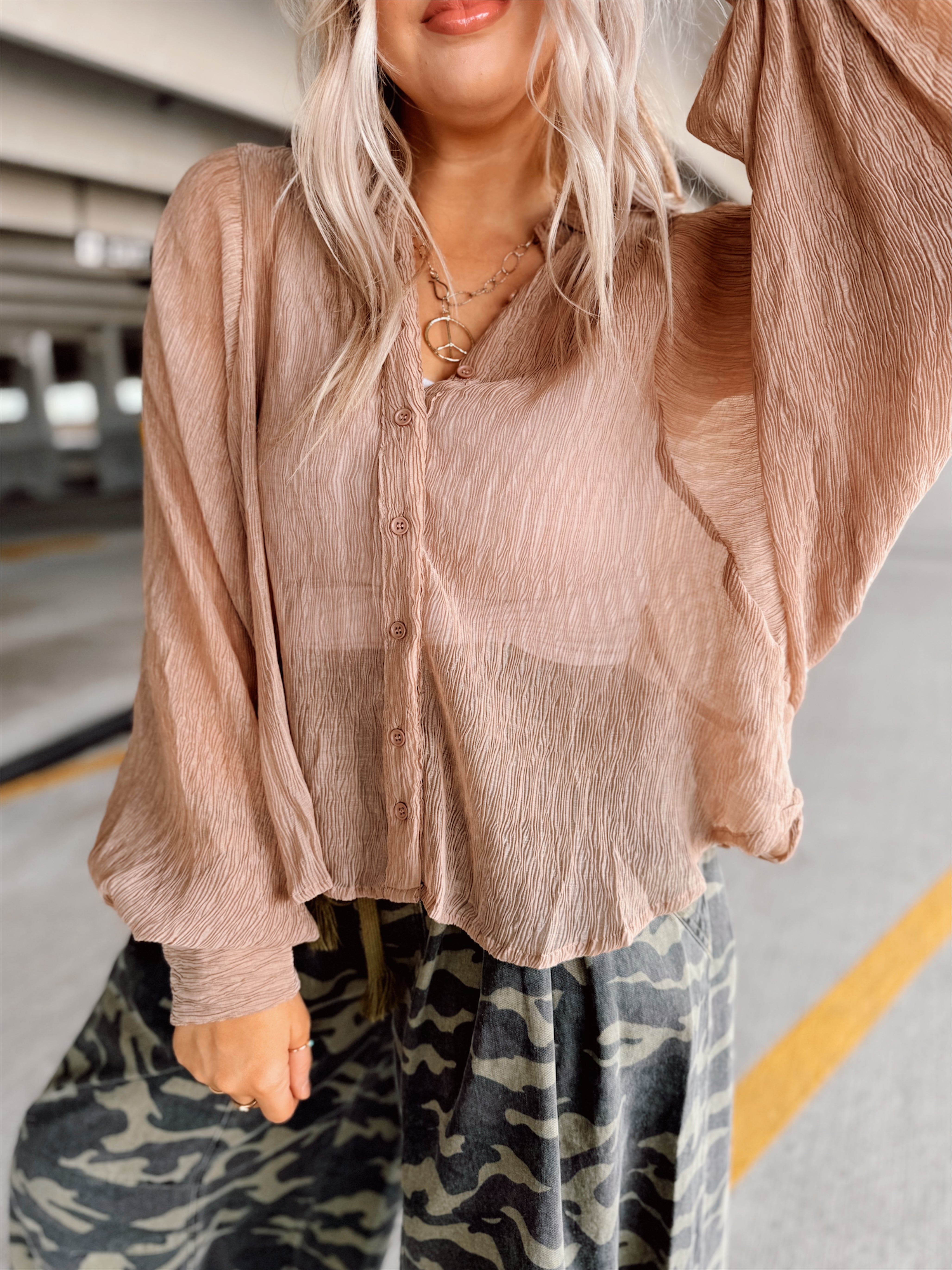 Woman in a brown top and camouflage pants standing in a parking garage