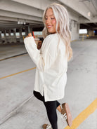 Woman in a white sweatshirt standing in an indoor parking garage.