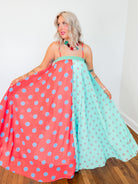 Woman holding a polka dot dress with pink and green colors.