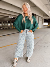 Load image into Gallery viewer, Person wearing a green top and light blue checkered patterned pants in a parking garage.