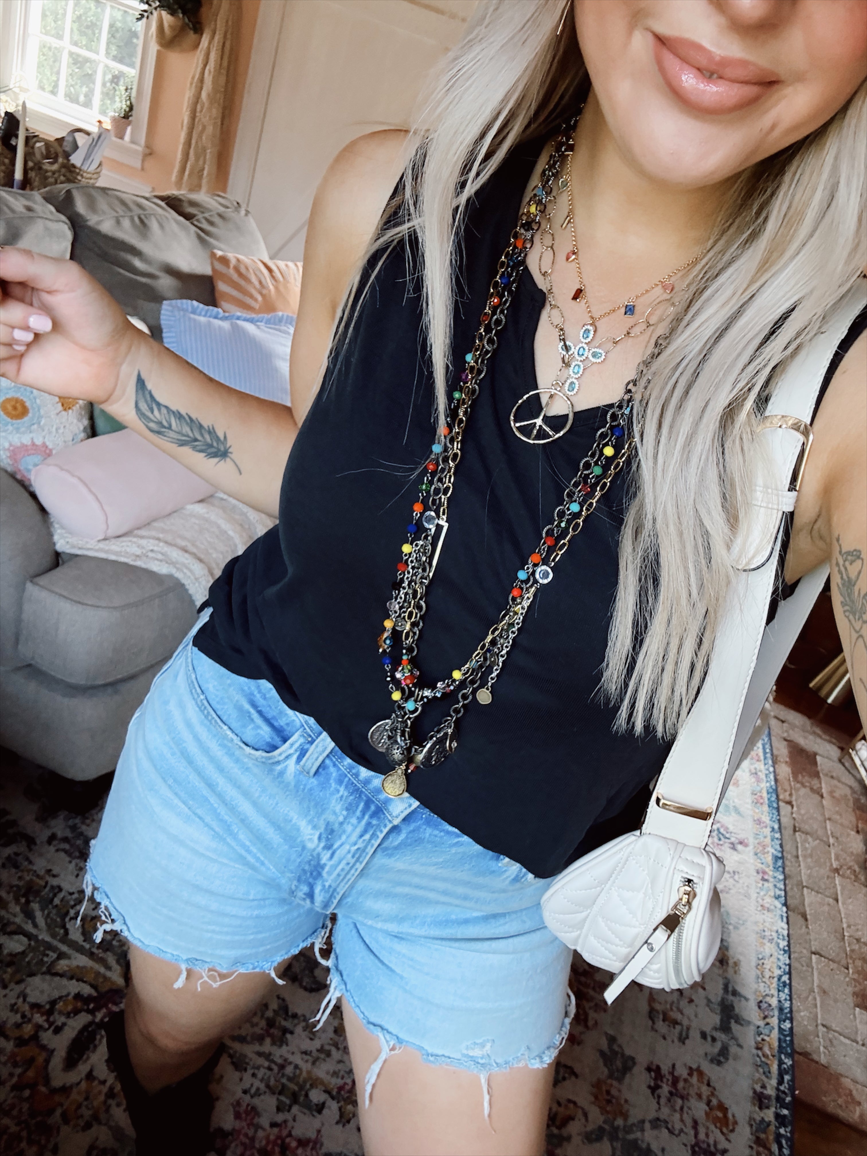 Woman standing with necklaces on in a living room. 
