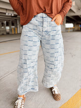 Load image into Gallery viewer, Person wearing a brown top and light blue checkered patterned pants in a parking garage.