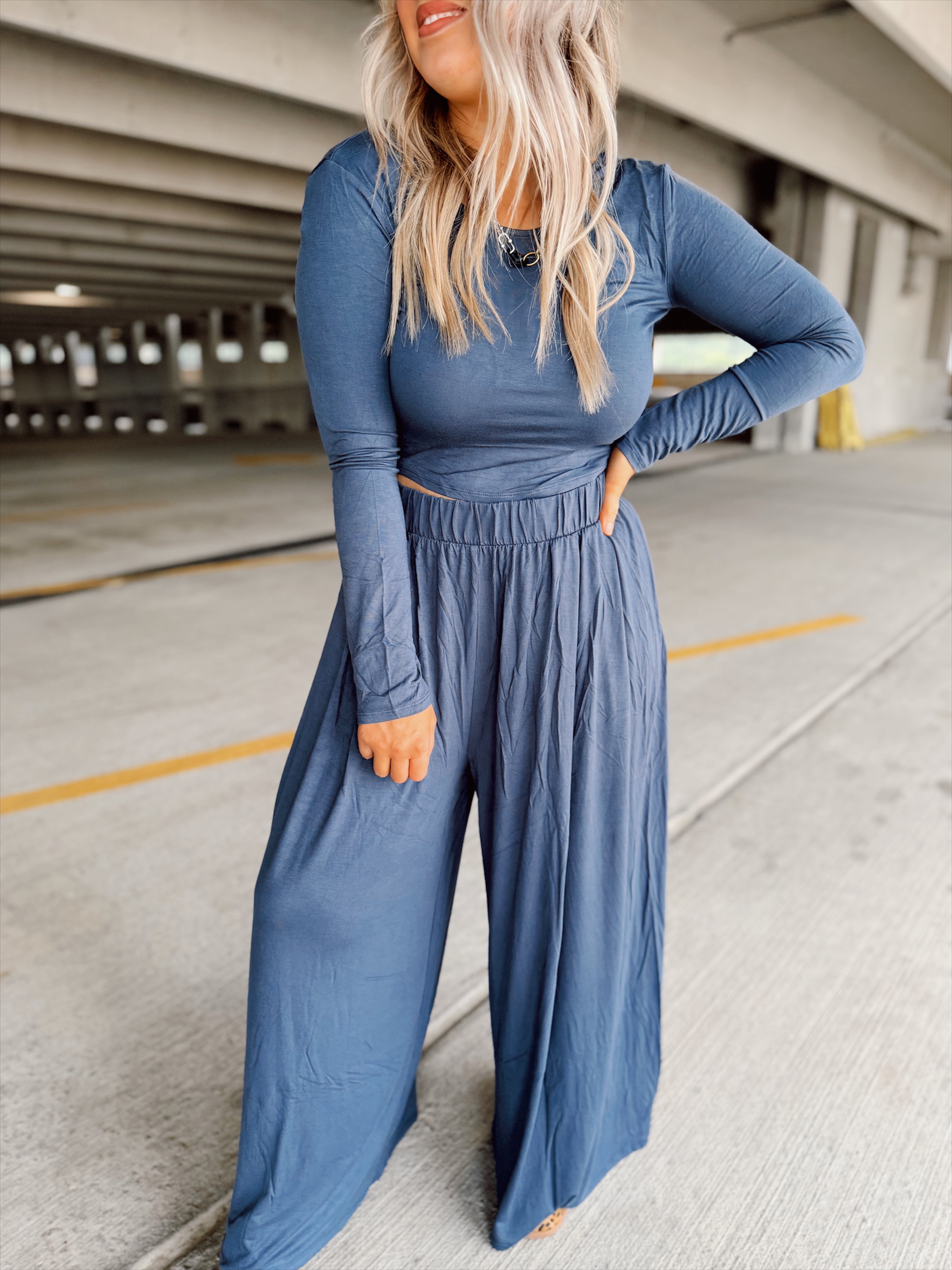 Person wearing a blue set standing in an parking garage.