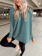 Woman wearing a green and white striped long-sleeve top and black leggings in a parking garage.