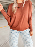 Person wearing a brown long-sleeve top and light blue checkered pants in aparking garage.
