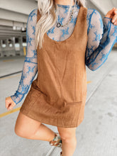 Load image into Gallery viewer, Woman in a brown suede dress with floral top and boots standing in an parking garage.