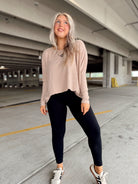 Woman in a beige striped top and black leggings standing in a parking garage.
