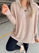 Person wearing a beige striped long-sleeve top and dark leggings in a parking garage.