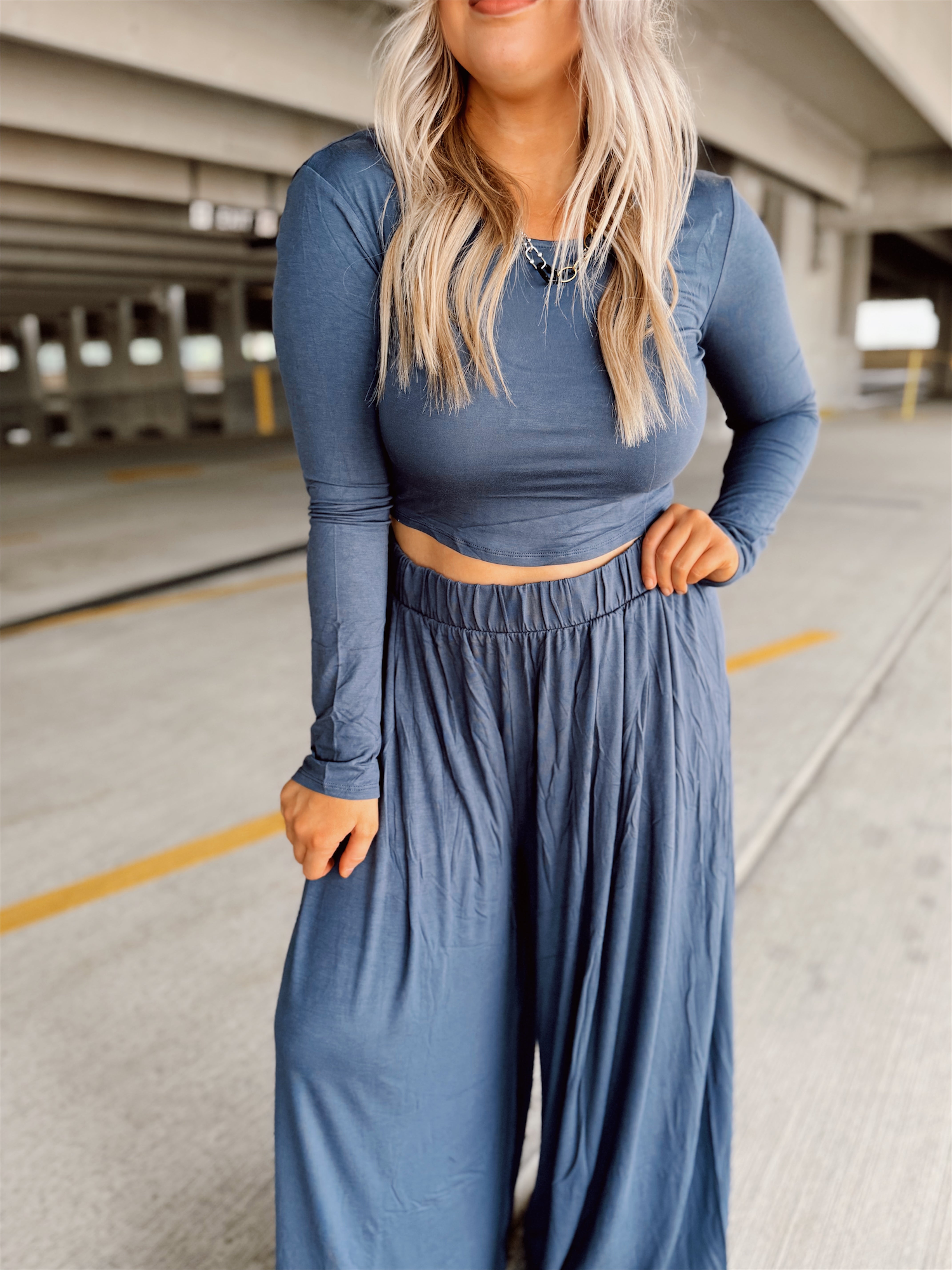 Person wearing a blue set standing in an parking garage.