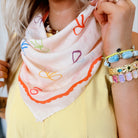 Person wearing a colorful scarf and multiple bracelets on a blurred background