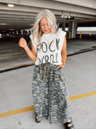 Woman wearing a sleeveless top with 'Rock Roll' text and camouflage pants in an underground parking lot.