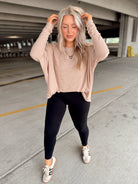 Woman in a beige long sleeve striped top and black leggings standing in an indoor parking garage.