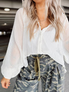 Person wearing a white blouse and camouflage pants in a parking garage.