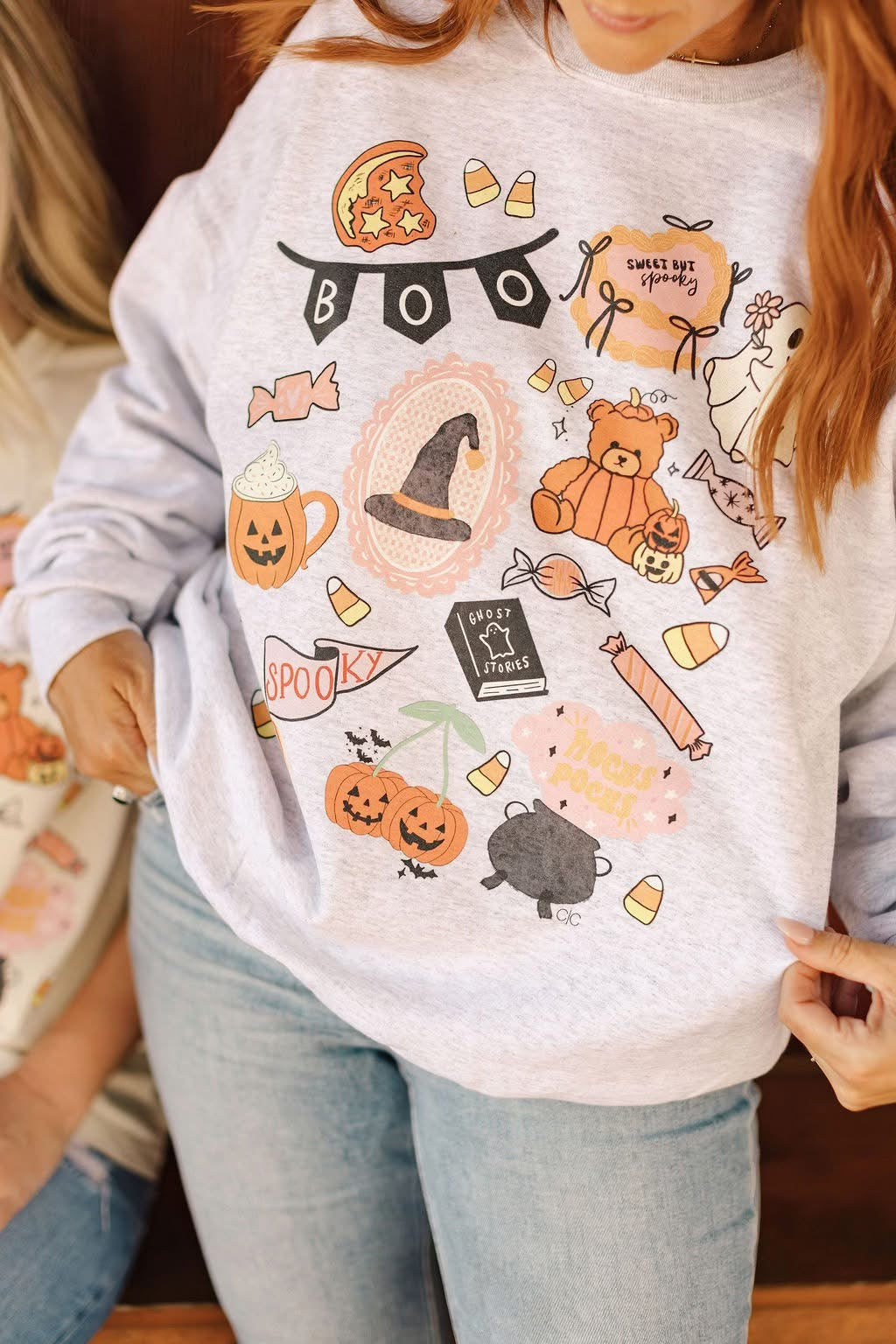 Person wearing a light gray sweatshirt with Halloween-themed graphics.