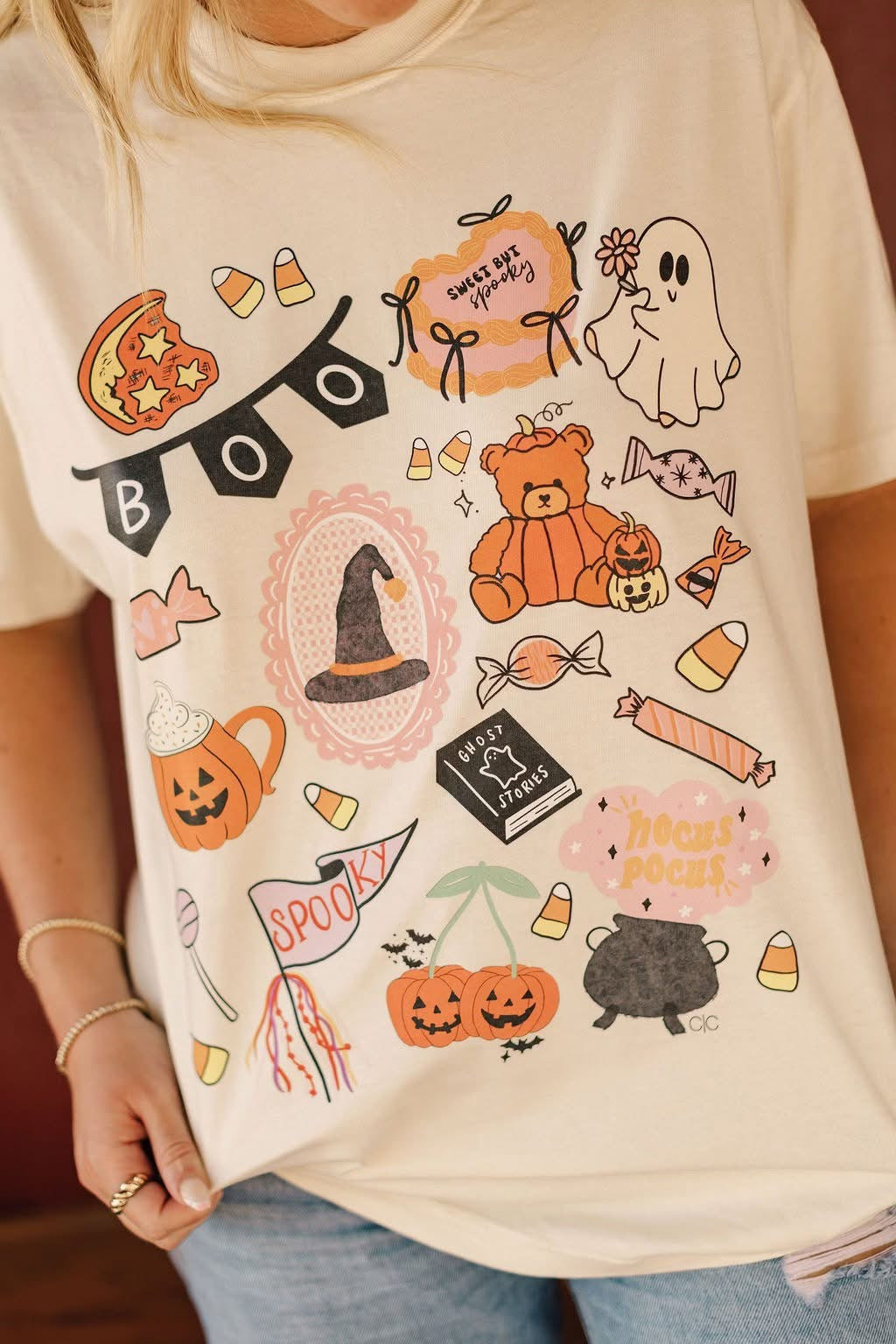 Beige t-shirt with Halloween-themed graphics worn by a person.